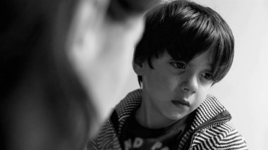 Gözyaşlarını silen genç bir çocuk, annesiyle konuşurken gözle görülür şekilde üzgün ve duygusal. Saf bir duygusal değişimi, sakin bir evde yakalıyor.