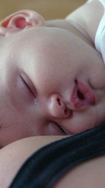 Bebeğin anne ve babasının göğsünde sessizce dinlenirken, huzurlu bir uyku anı, yumuşak bir nefes ve yumuşak bir yüz ifadesiyle.