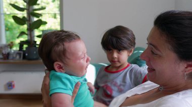 Anne kucağında ağlayan bir bebekle ağlarken ağlayan abim evde şefkatle ve özenle aile içi etkileşimi ve duygularını gösteriyor.