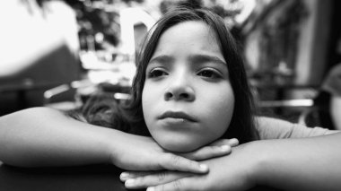 Siyah ve beyaz, genç bir kızın elleri üzerinde çenesini dinlendirirken, düşünceli bir şekilde uzaklığa bakarken. Doğal bir doğa ortamında iç gözlem anı