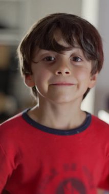 Genç çocuk sıcak bir şekilde gülümsüyor, doğrudan kameraya bakıyor, neşeli ve neşeli bir yüz ifadesi, masum ve mutlu bir anı yakalıyor.