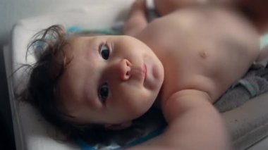 Bebek masa değişiminde, odaklanmış ifade, hafif kaşlar çatma, bebek bezi değişimine hazırlık, titizliğin ilk aşamaları, günlük rutin, rahat vücut duruşu.