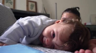 Bebek kanepeye uzanmış neşeli bir ifadeyle, dinleniyor ve gülümsüyor, neşeli ve mutlu bir bebek, annesiyle birlikte evde, aile içinde, dünyayı rahatça keşfeden bir bebek.