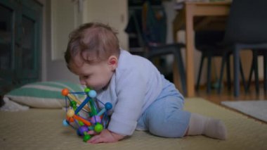 Bebek yerde oturuyor, neşeli bir oyuncakla oynarken neşeyle gülüyor, neşeli ve eğlenceli bir keşifle meşgul, sıcak bir ev ortamında eğlenceli aile vakitlerinin tadını çıkarıyor.