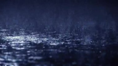 Koyu mavi ışığın altında yere düşen yağmur, ıslak bir yüzey üzerinde su damlacıklarının sıçraması ve dalgalanmalar oluşturduğu sakin ve sakin bir manzara yaratıyor.