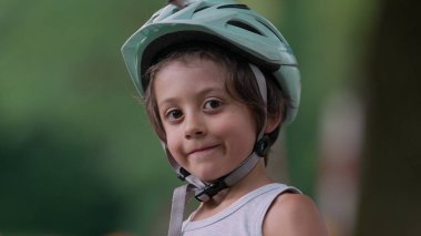 Kask takan genç bir çocuğun yakın plan portresi, kurnaz bir gülümsemeyle kameraya bakıyor. İfadesi, bir açık hava macerasının özünü, özgüvenini ve hazırlığını yansıtıyor.