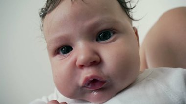 Bir bebeğin yüzüne yakın çekim, geniş, meraklı gözleri ve yumuşak yüz hatlarını gösteriyor. Bebek ifadesi merakla doludur.