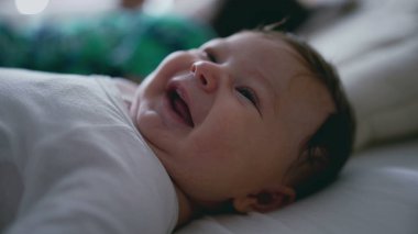 Bebeğin sırtüstü yatışı, meraklı gözlerle yukarı bakışı ve hafif aralıklı dudakları bebeğin huzurlu ifadesini ve narin özelliklerini gösteriyor.