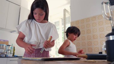 Genç bir kız fırın tepsisine hamur sıkıştırırken bir oğlan mutfakta onun yanında çalışıyor. Bir aile pişirme oturumu sırasında konsantrasyon ve takım çalışması