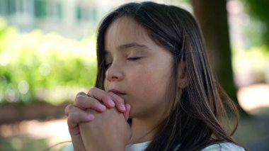 Gözleri kapalı, elleri dua pozisyonunda birbirine kenetlenmiş ruhaniliği, umudu ve inancı sembolize eden bir kız. barışçıl yansıma