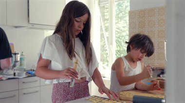 Genç bir kız mutfak aletleriyle hamur sıkıştırmaya odaklanırken bir oğlan onun yanında dikkatlice çalışıyor. bir ev yapımı oturum sırasında konsantrasyon ve beceri