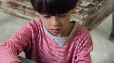 Oyuncak uçağı konsantrasyonuyla monte eden genç çocuk, oyun zamanı boyunca ev ortamında dikkatli bir şekilde parçaları yerleştirmeye odaklanıyor.