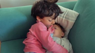 Ağabeyim, kanepede yan yana uzanırken bebeklerin elini öpüyor. Sevgi ve ilgi dolu bir kardeş anı. Yakınlık ve sevgi dolu bir yuva kuruyor.