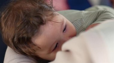 Emziren bir bebeğin yakın çekimi, sakin ve samimi bir bakım anında gözleri kapalı huzur içinde dinleniyor.
