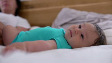Yatağa uzanmış gülümseyen bir bebeğin rahat bir aile ortamında huzurlu bir anın tadını çıkarırken.