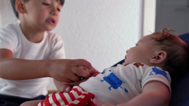 Küçük çocuk bir fedainin elini tutmak için elini uzatıyor, yakın bir aile bağı içinde sevgi ve şefkat gösteriyor, evde özen ve etkileşim gösteriyor.