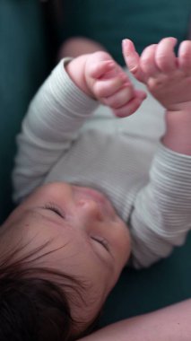 Bebek birlikte kanepede uzanıyor, huzurlu bir ifadeyle yukarıya bakıyor, aile ortamında rahatça dinleniyor.