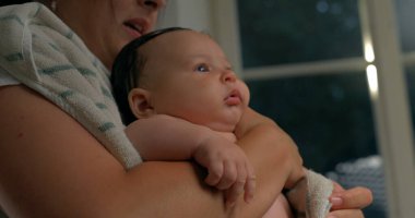 Bebek banyodan sonra yukarı bakıyor, havluya sarılmış, sakin ve dikkatli, banyo sonrası samimi bir bakım, yakın çekim. 800 fps yavaş çekim