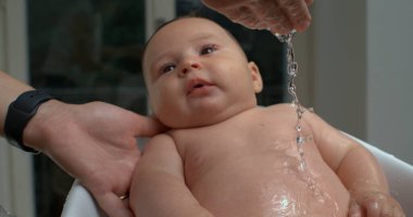 Banyo sırasında bebek göğsüne su döküldü, bebek gülümsedi ve baktı, rahatlatıcı ve rahatlatıcı banyo bakımının keyfini çıkardı. 800 fps yavaş çekim