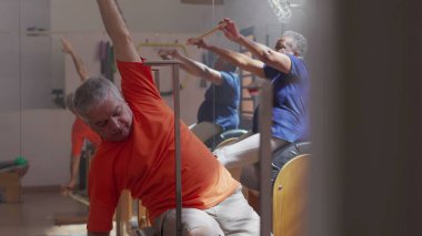 Üst düzey erkek ve kadın pilates grup seansında güç ve esneklik kazanıyor. Yaşlılık spor yaşam tarzını geliştirir..