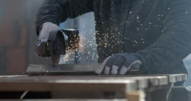 Açı öğütücüsüne yakın çekim. 800 fps hızla hareket eden kıvılcımlarla metali kesiyor. Eldivenli işçiler ellerini sabit tutuyor, hassasiyet ve güvenliğe odaklanıyor. 