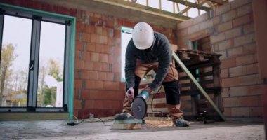 Açı öğütücü kullanan işçiler, metal kesiminden kıvılcımlar saçan, kapalı inşaat alanı, güvenlik ve hassasiyet odaklı, koruyucu başlık ve dişli