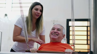 Pilates Kadın Koçu 'nun yardımıyla egzersiz yapan mutlu kıdemli adam. Yaşlı insan rutin egzersiz yaparak güç ve refah kazanıyor..