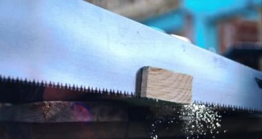 Tahta bloğu kesen el testeresi, havaya saçılmış talaş, yavaş çekimde detaylı marangozluk işi, hassas DIY yapısı, 800 fp.