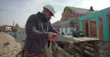 Derme çatma tezgahta odun kesen inşaatçı, arka plandaki bina, göreve odaklanmış, yapım aşamasındaki yapı, iş başında yetenekli işçilik