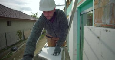 İskele üzerinde havan topu, miğferli inşaat işçisi ve arka planda merdiven, konut binasının ön cephesinde yalıtım için hazırlık