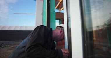 İnşaat alanındaki pencere çerçevesini denetleyen, konut inşaatı projesinin doğruluğu ve kalitesine odaklanan bir işçi