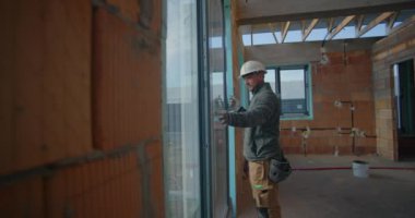 Konut inşaatı sırasında pencere kurulumunu denetleyen işçiler, başlık takarak, yerleşim yerinde hizalama ve kalite standartları sağlayarak,