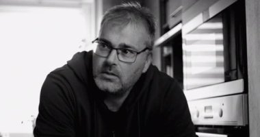 Tezgaha yaslanan adama yakın çekim, yansıtıcı ifade, modern mutfak arka planı, düşünceli bir duruşu olan kişisel evcil an, siyah-beyaz