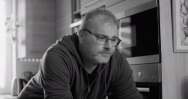 Mutfak tezgahına dayanan adam, düşünceli ifade, sabah içkisi, monokromatik stil, modern ev dekorasyonu, doğal ışık ile günlük ev hayatı