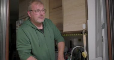 Eller mutfak lavabosunda akan suyun altında bir deniz mavisi kasesini yıkıyor, rahat bir evde temizlik ve günlük ev işleri yapmaya odaklanıyor.