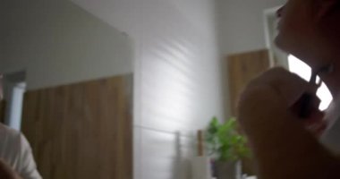 Boynunun altını tıraş ederken aynaya bakan, traş bıçağı ile kusursuz darbeler, doğal banyo geçmişi, aile ortamında kişisel bakım rutini