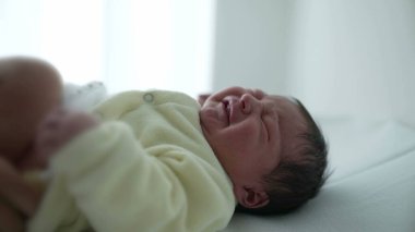 Hemşire hastane rutini sırasında bebek bezi değiştirirken bebek rahatsız oluyor. Yeni doğan bakımının temel unsurları, bebek hijyeni için gerekli hassas ve dikkatli bakımı vurguluyor