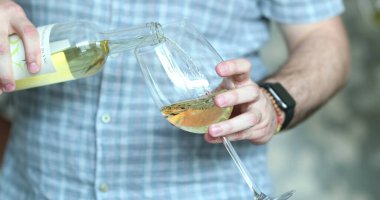 pouring white wine, hand closeup