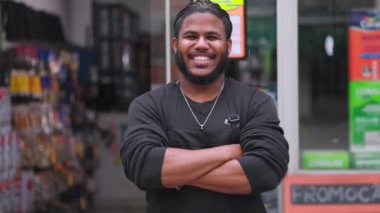 Önlüklü gülümseyen adam boyacı dükkanının önünde kollarını kavuşturmuş, arkadaşlığı ve boya endüstrisindeki perakende satış uzmanı rolüne güveni somutlaştırıyor.