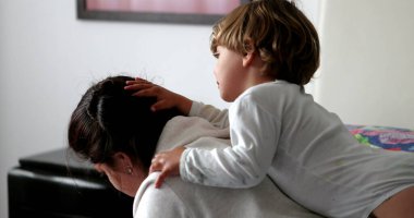 İçten bir aile anı, bebek sarılan anne saçı.