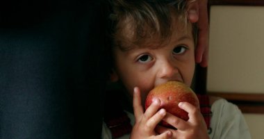 Küçük çocuk elma yiyor, çocuk sağlıklı atıştırmalıklar yiyor.