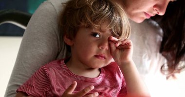 Çocuk elleriyle yüzünü siliyor, çocuk yüzüne dokunuyor.