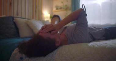 Yatakta ellerini tutarak uzanan kadın, duygusal karmaşa ve hassasiyetle mücadele ediyor, zihinsel sağlık ve kişisel kriz temaları