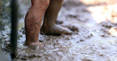 Çamurda zıplayan bebek ayakları. Islak çamurda ayakta duran çocuk ayakları