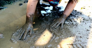 Yakından çekilen eller çamurla oynuyor.