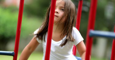 Kız maymun barına tırmanıyor. aktif Küçük çocuk oyun alanında oynuyor