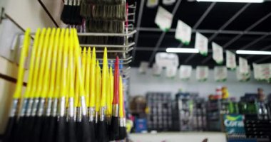 Resim fırçasını bir boya dükkanının rafına yerleştiren bir elin yakın çekimi, örgütlenmeye ve renkli malzemelerin düzgün bir şekilde gösterilmesine odaklanıyor.