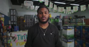 Profesyonel bir adam arka planında boya kutuları ve malzemelerle boya dükkanında duruyor. Perakende sektöründe odaklanmış bir işçi.