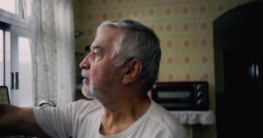 Mutfak penceresinden dışarı bakan yaşlı bir adam içsel bir ifadeyle, yalnızlığı, yaşlanmayı ve günlük hayattaki kişisel yansımaları temsil ediyor.