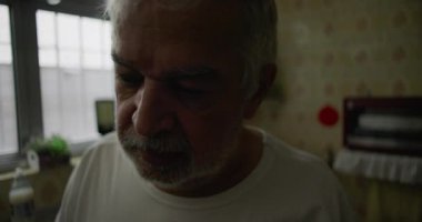 Mutfaktaki yaşlı adamın içsel ifadesiyle, yalnızlığı, yaşlanmayı ve ev hayatındaki sessiz yansımaları temsil eden yakın çekimi.
